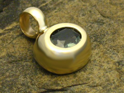 Runder goldener Anhänger mit synthetischem Turmalin, Gold 333, gefertigt vom Juwelier Harnisch. Der Anhänger hat eine glatte Oberfläche und einen facettierten Stein in der Mitte.