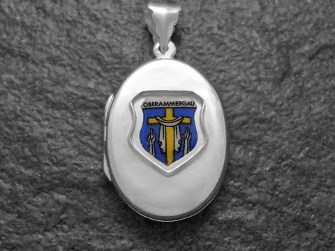 Silbernes Medaillon mit dem Stadtwappen von Oberammergau, das auf einem blauen Hintergrund eine goldene Figur zeigt, in einem eleganten Design, hergestellt von Juwelier Harnisch aus Bayern.