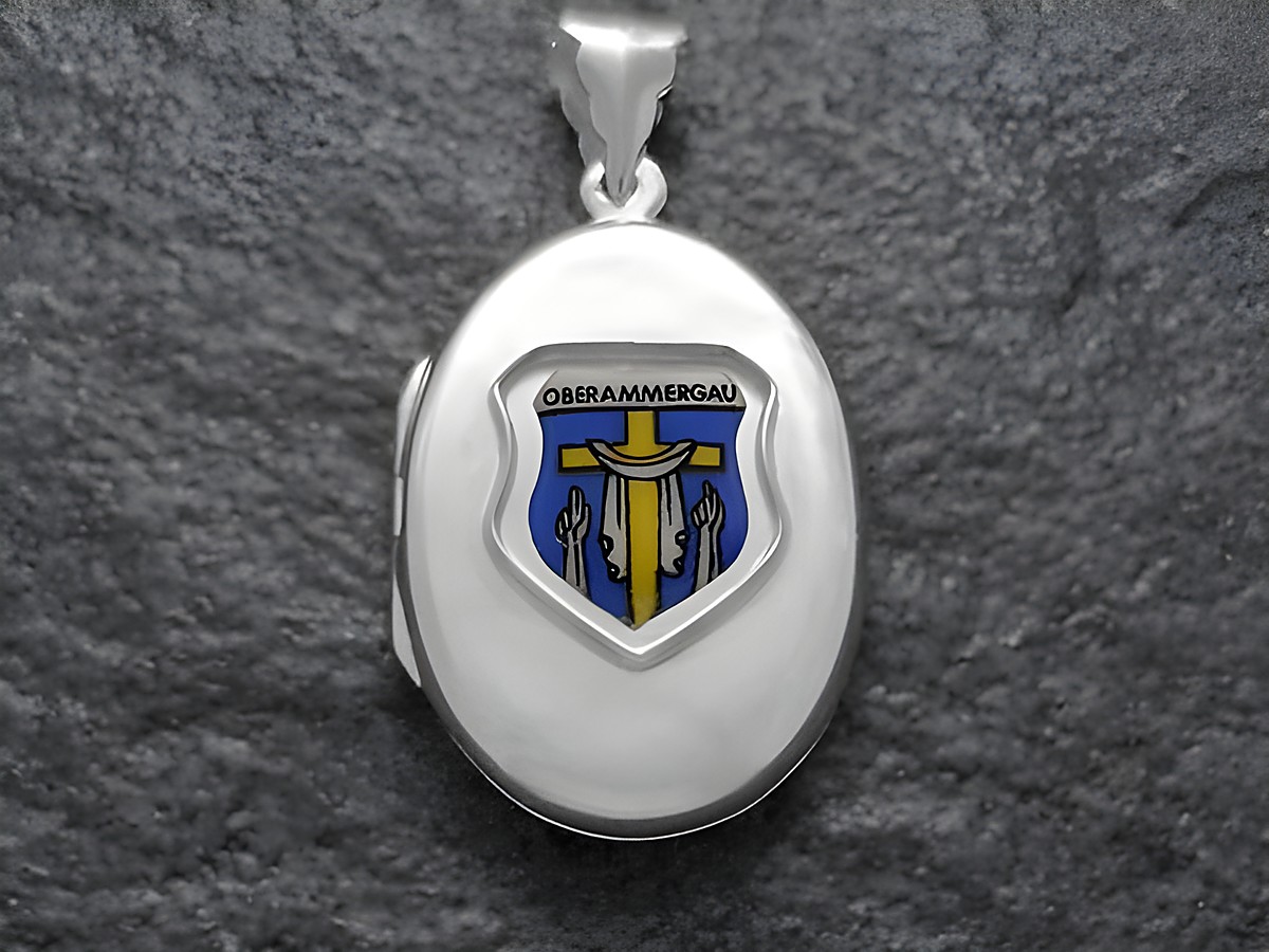 Silbernes Medaillon mit dem Stadtwappen von Oberammergau, das auf einem blauen Hintergrund eine goldene Figur zeigt, in einem eleganten Design, hergestellt von Juwelier Harnisch aus Bayern.