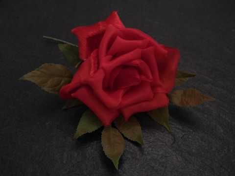 Haarschmuck mit einer roten Samt-Mix-Blume und grünen Blättern, verspielt gestaltet, Hersteller Juwelier Harnisch, ideal für besondere Anlässe oder zum Ergänzen von Outfits.
