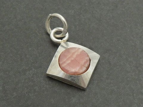 Silber Anhänger rhodiniert mit quadratischem Design und einem runden Rhodochrosit in rosa Farbton, hergestellt von Juwelier Harnisch. Der Anhänger ist feminin und elegant.