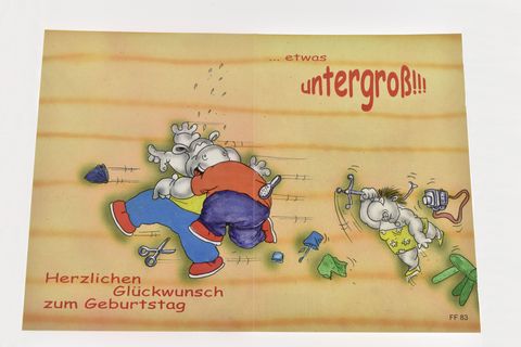 Eine bunte Geburtstagskarte mit comicartigen Nilpferden, die fröhlich lachen. Ein Nilpferd ist gerade dabei, ein Geschenk auszupacken, während das andere ihm begeistert zusieht. Der Text wünscht herzlichen Glückwunsch zum Geburtstag.