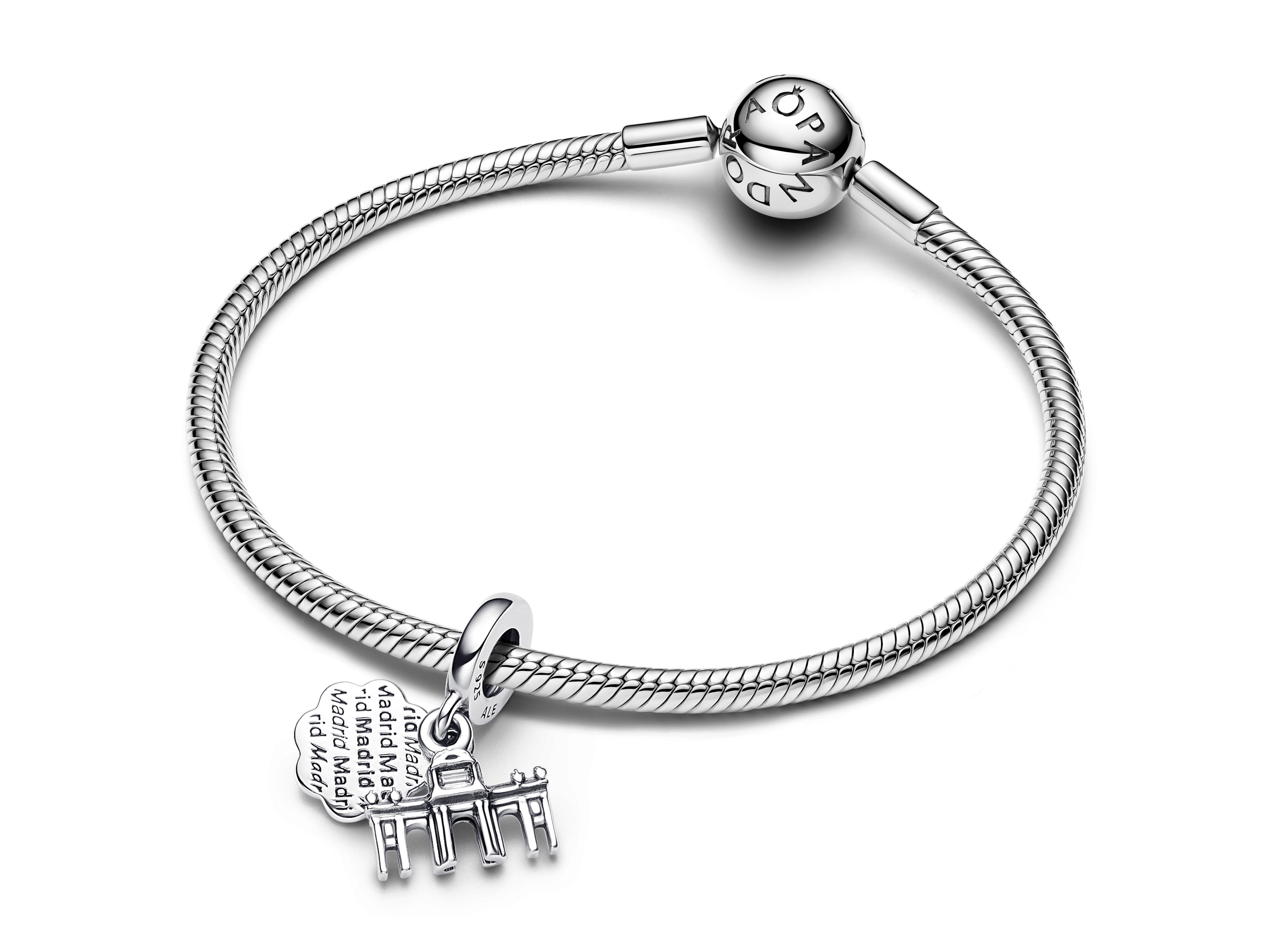 Ein silbernes Armband von Pandora mit dem charm Puerta de Alcala, der das berühmte Wahrzeichen Madrids zeigt. Der Charm enthält auch eine Schrift mit dem Stadtname.