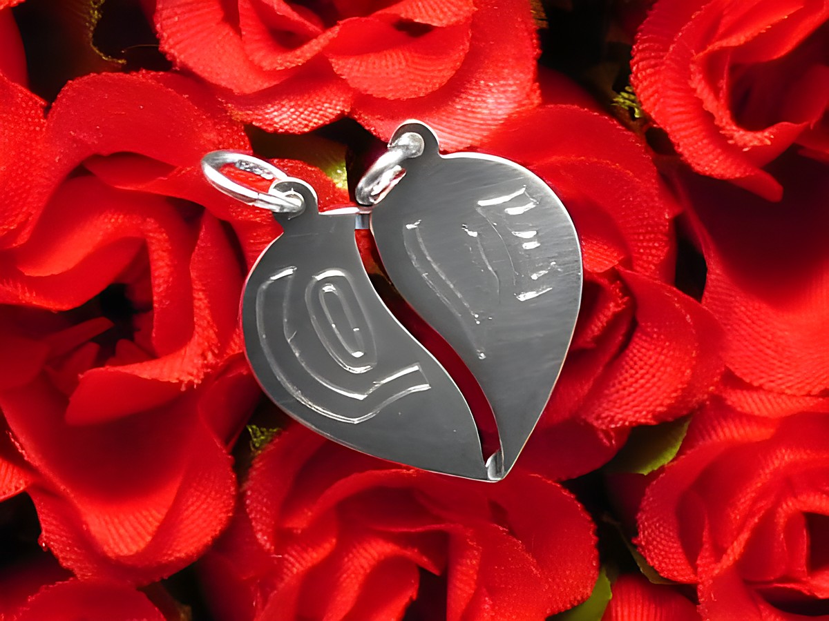 Herz Partneranhänger aus Silber, teilt sich in zwei Hälften, mit feiner Liniengravur, umgeben von roten Rosen, symbolisiert Freundschaft und Verbundenheit, Hersteller Juwelier Harnisch.