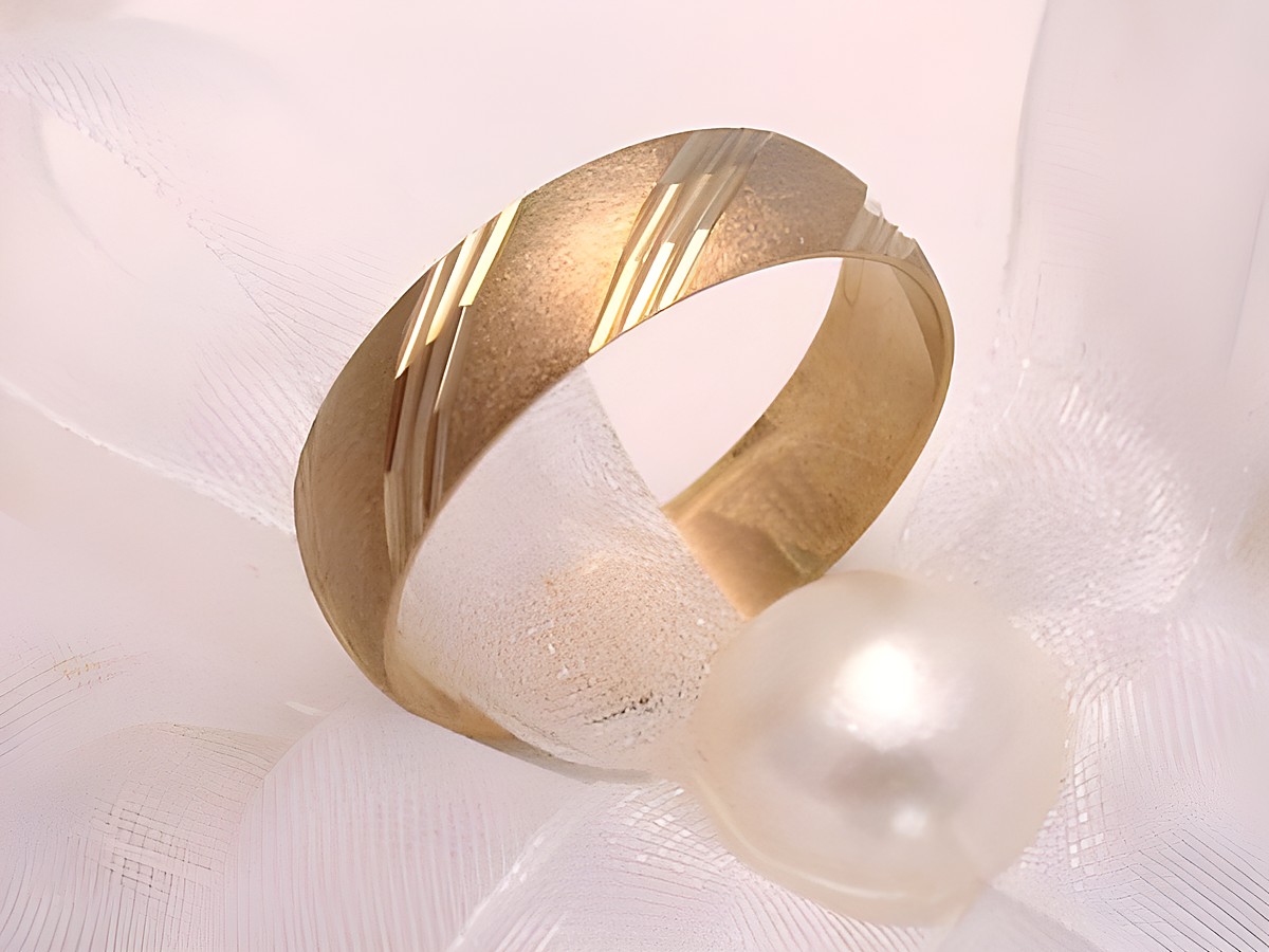 Trauring Ehering PRETTY in Gold 333 Gr. 54/17,2 von Juwelier Harnisch, elegant mit dekorativer Oberflächenstruktur, liegt auf weißem Organza und einer Perle.