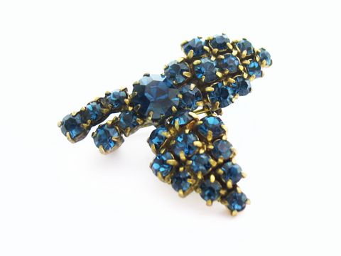 Blaue Strass Brosche in blumenförmigem Design von Juwelier Harnisch, ideal für einen sexy City Look, funkelt in verschiedenen Blautönen und verleiht jedem Outfit einen eleganten Akzent.