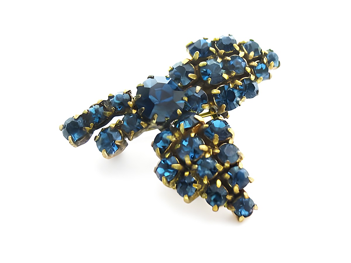 Blaue Strass Brosche in blumenförmigem Design von Juwelier Harnisch, ideal für einen sexy City Look, funkelt in verschiedenen Blautönen und verleiht jedem Outfit einen eleganten Akzent.