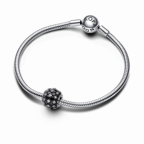 Funkelndes rundes schwarzes Pavé-Charm aus Sterling Silber mit einem Steinmix in Schwarz, auf einem silbernen Armband angebracht. Hersteller ist Pandora.