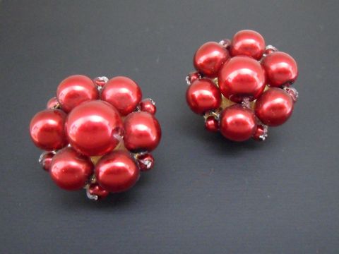 Ohrclip in dunklem Rot mit blumigem Design, ergänzt durch goldfarbene Elemente und synthetische Zuchtperlen, hergestellt von Juwelier Harnisch.