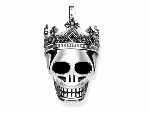 Ein silberner Anhänger in Form eines Totenschädels mit einer Krone, verziert mit schwarzen und klaren Steinen, aus der Rebel at Heart Kollektion von Thomas Sabo.