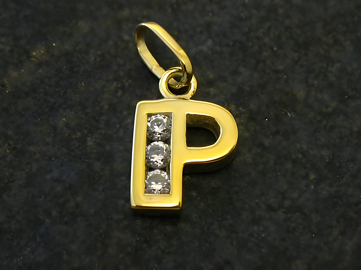 Ein goldener Anhänger in Form des Buchstabens P mit drei eingelegten Zirkonia-Steinen. Der Anhänger stammt vom Juwelier Harnisch und ist elegant gestaltet.