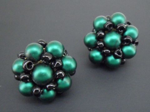 Ohrclip in dunkelgrün-schwarz mit blumigem Design und goldfarbenen Details, gefertigt aus seidenmatten synthetischen Zuchtperlen, Hersteller Juwelier Harnisch.