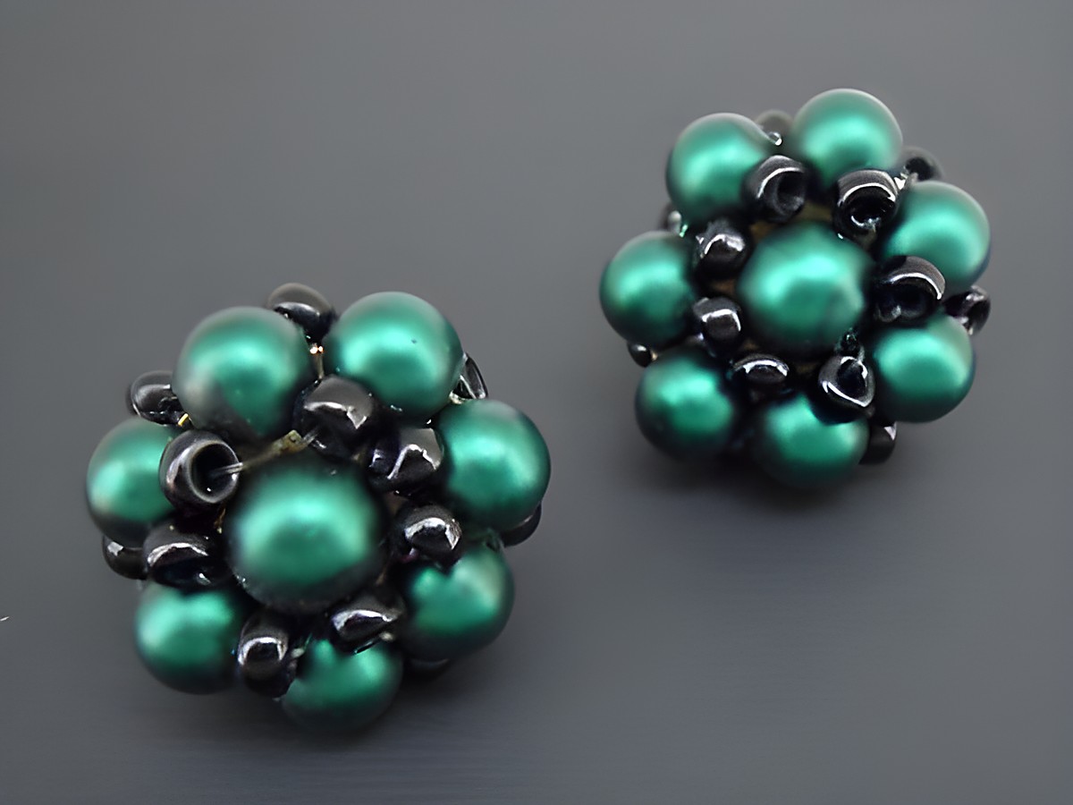 Ohrclip in dunkelgrün-schwarz mit blumigem Design und goldfarbenen Details, gefertigt aus seidenmatten synthetischen Zuchtperlen, Hersteller Juwelier Harnisch.