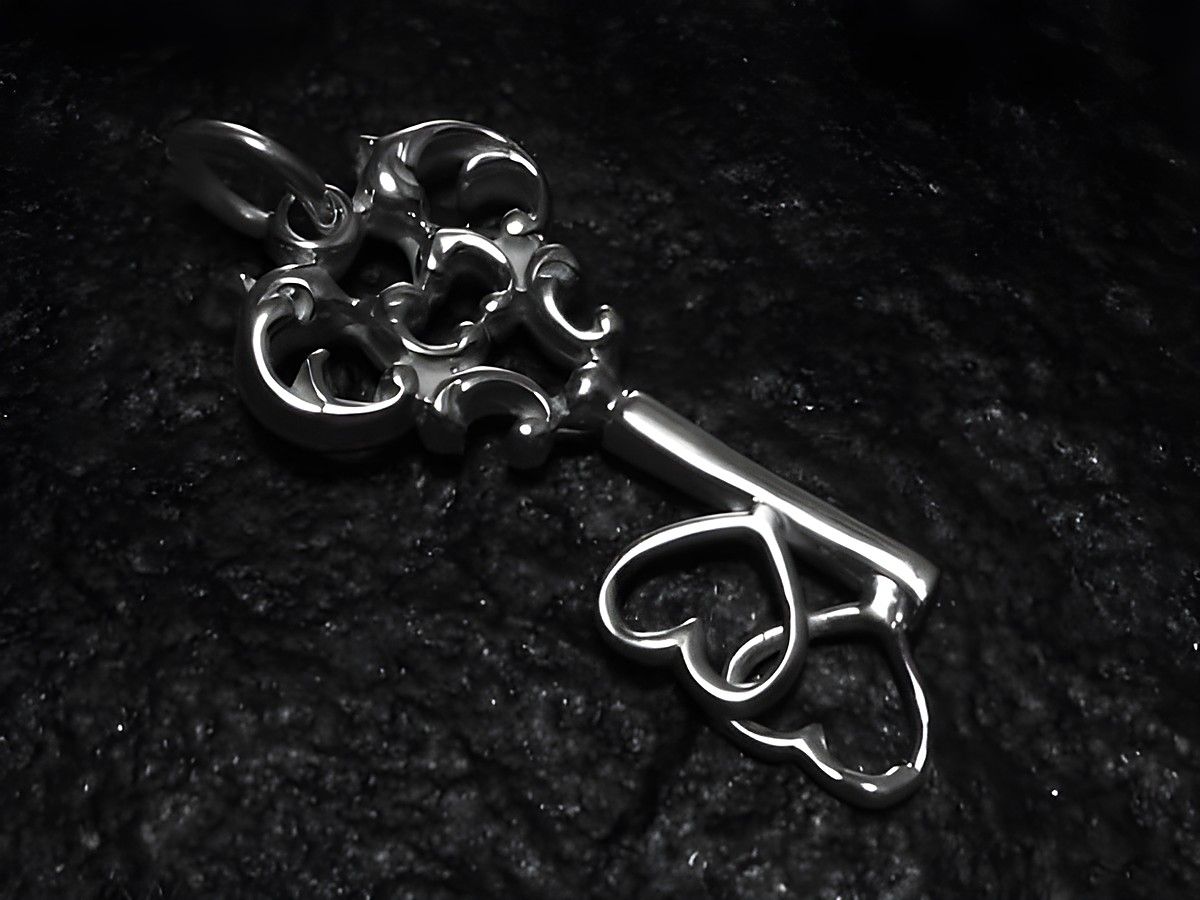Schlüssel zum Herzen, Sterling Silber Anhänger von Juwelier Harnisch, filigranes Design mit herzförmigen Elementen, glänzende Oberfläche, romantisches Schmuckstück.