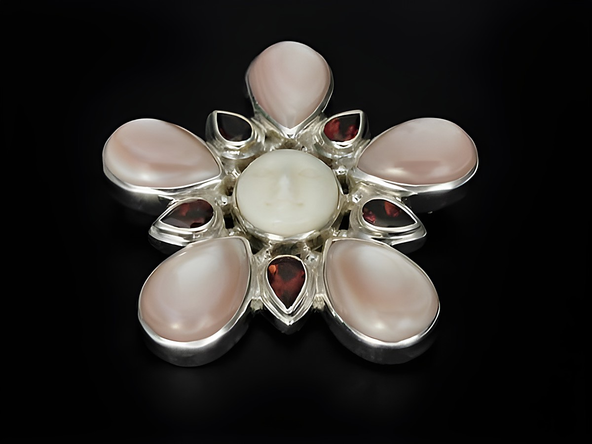 Silber Brosche und Anhänger aus rotem Perlmutt und Granat in Form einer blühenden Blüte, hergestellt von Juwelier Harnisch, mit einem faszinierenden Gesicht in der Mitte.