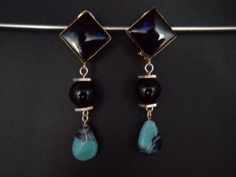 Schwarze und türkisfarbene Ohrclips mit zeitlosem Design, goldfarbene Akzente aus Kunstharz, exklusiv vom Juwelier Harnisch, ideal für elegante Anlässe.