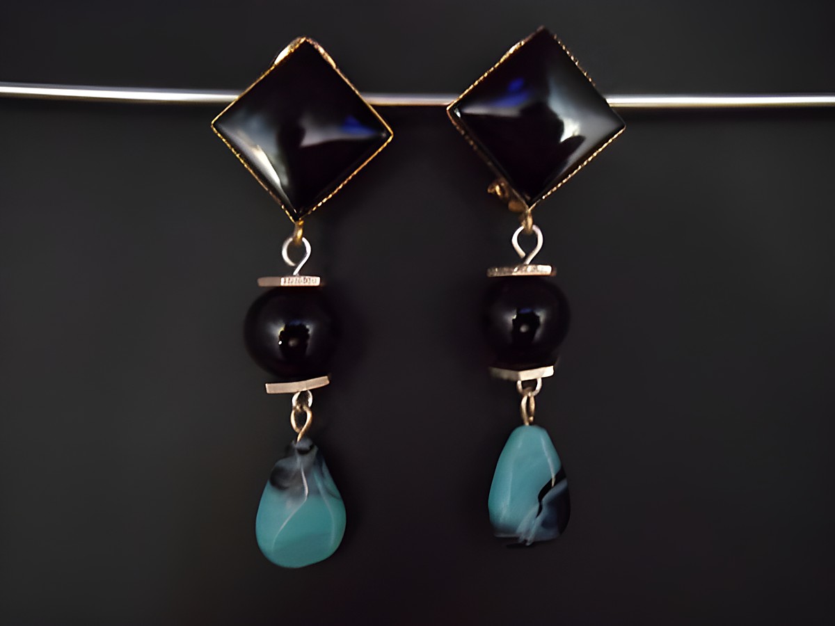 Schwarze und türkisfarbene Ohrclips mit zeitlosem Design, goldfarbene Akzente aus Kunstharz, exklusiv vom Juwelier Harnisch, ideal für elegante Anlässe.