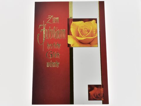 Eine Glückwunschkarte in Rot mit der Aufschrift Zum Jubiläum. Auf der Karte ist eine gelbe Rosenblüte abgebildet, die einen festlichen und eleganten Eindruck vermittelt. Hersteller Juwelier Harnisch.