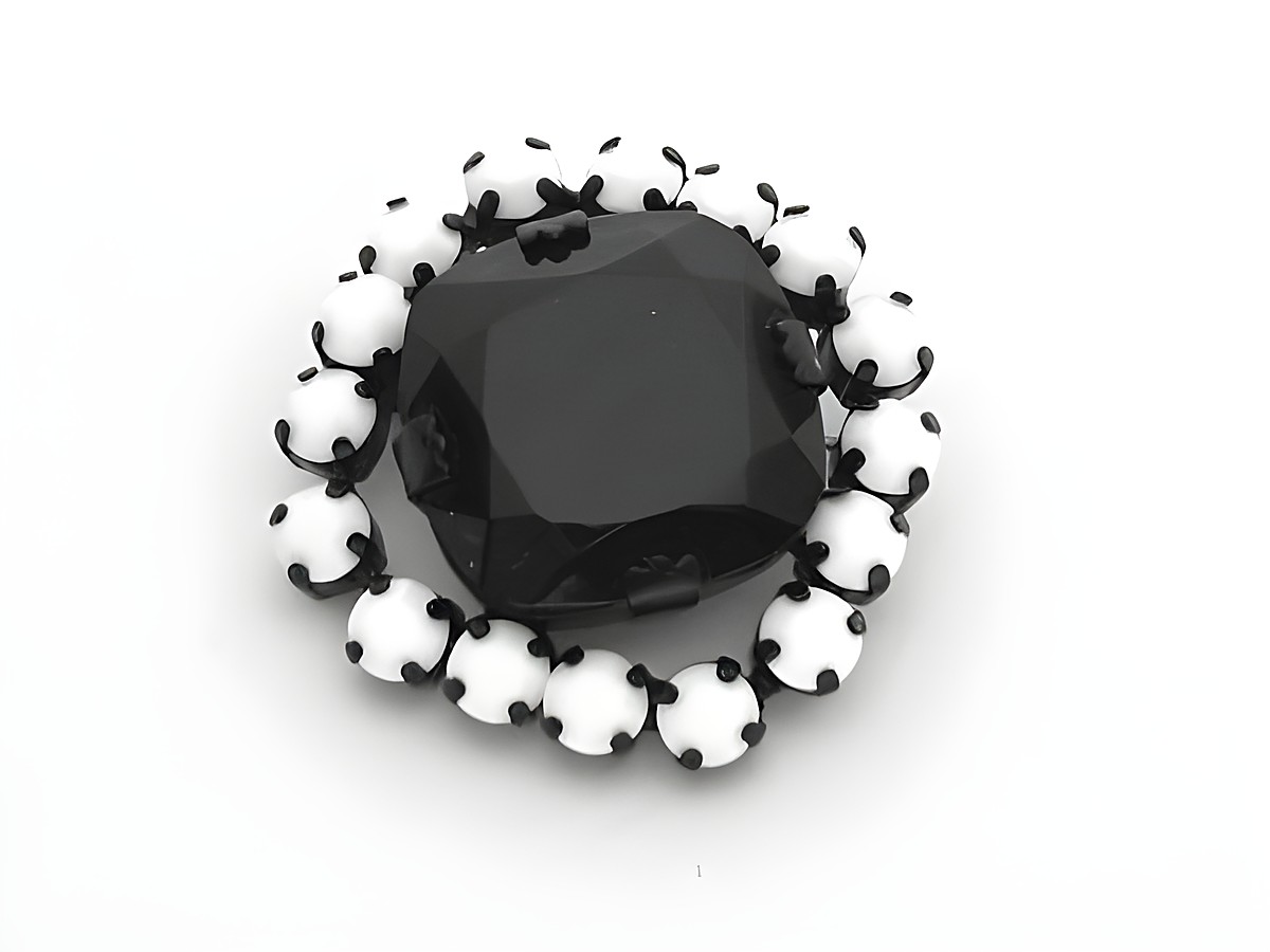 Strass Brosche in Weiß und Schwarz, rundlich gefasst, mit einem zentralen schwarzen Stein und umliegenden weißen Strasssteinen, Hersteller Juwelier Harnisch, elegant und zeitlos.
