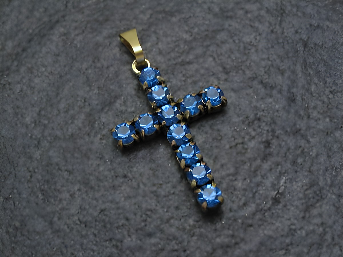 Blauer Strass Anhänger im sexy City Look in Kreuzform, Hersteller Juwelier Harnisch, verziert mit glitzernden blauen Strasssteinen auf einer eleganten goldfarbenen Fassung.