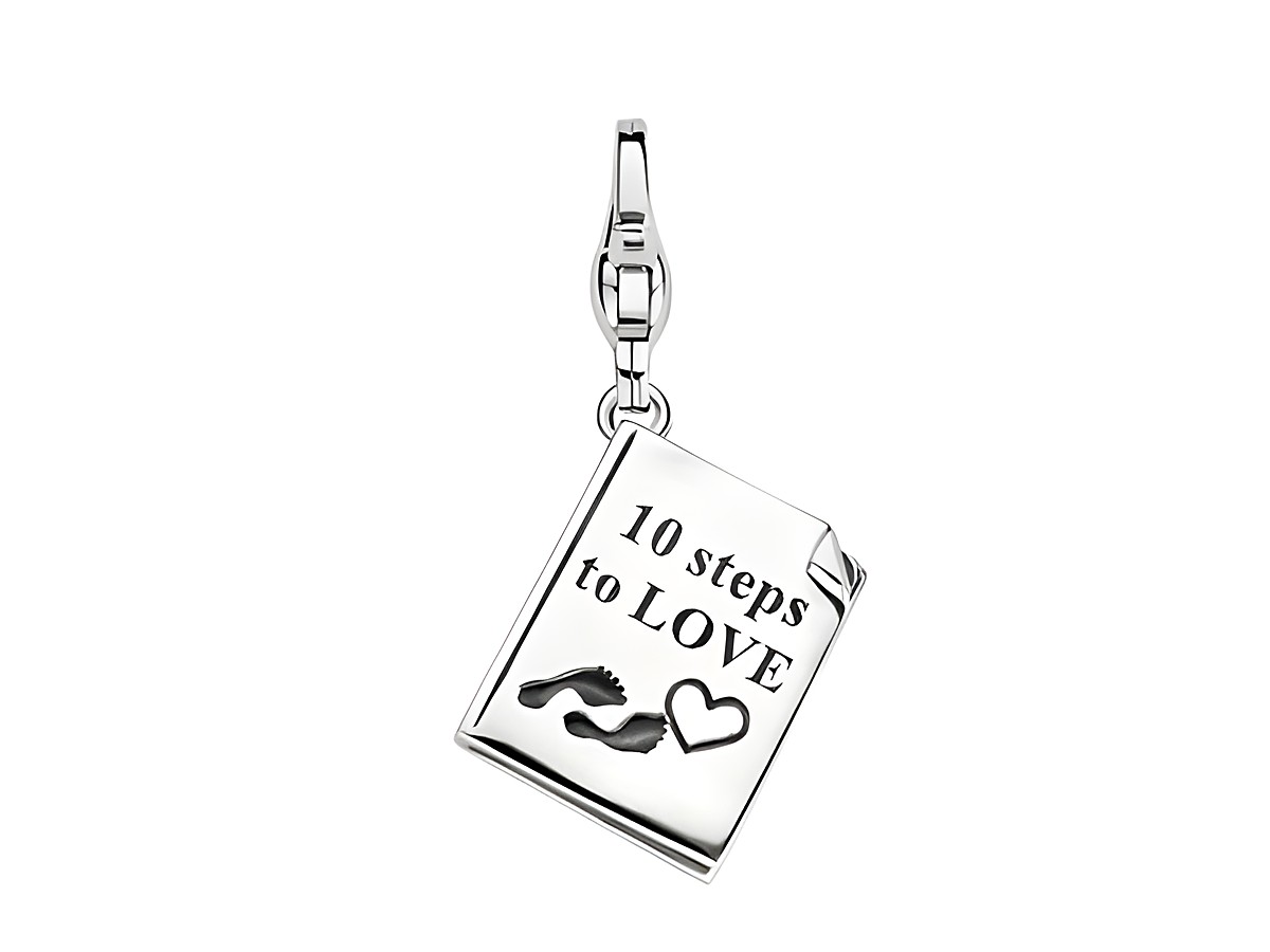 Ein silberner Charm in Form eines aufgeschlagenen Buches mit der Aufschrift zehn Schritte zur Liebe, verziert mit Fußabdrücken und einem Herz, hergestellt von Ti Sento.