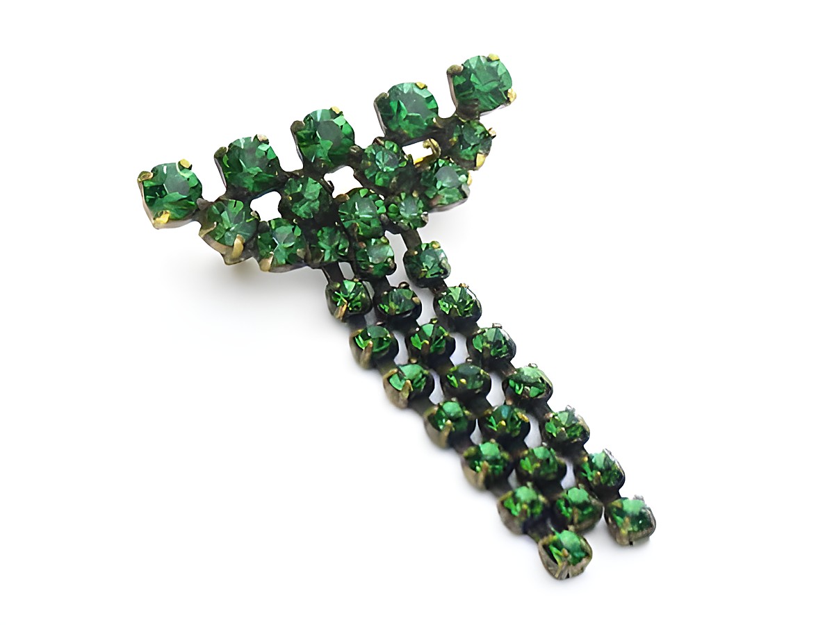 Grüne Strass Brosche in elegantem Sexy City Look von Juwelier Harnisch, besteht aus funkelnden grünen Strasssteinen in dekorativem Design. Ideal für stylische Akzente.