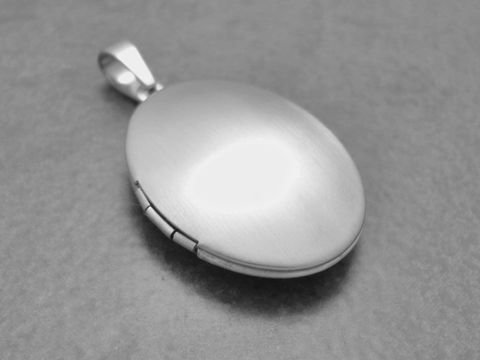 Ovales, schlicht mattiertes Medaillon aus Edelstahl, hergestellt von Juwelier Harnisch. Ideal als Anhänger für persönliche Erinnerungen oder als stilvolles Schmuckstück.