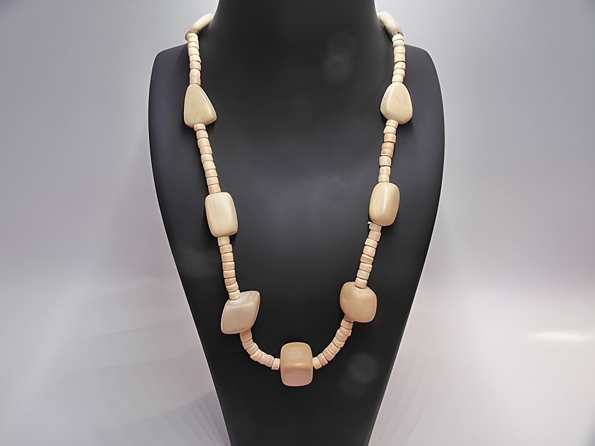 Holzkette Multiform 25 mm naturbraun 60 cm Holz Schmuck von Juwelier Harnisch, bestehend aus verschiedenen holzfarbenen Formen und unterschiedlichen Längen, elegant präsentiert auf einem schwarzen Schmuckständer.