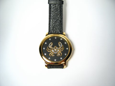 Krebs Sternzeichen Uhr mit schwarzem Zifferblatt, goldener Uhrmacherplatte und krustentierartigen Motiv, 23 cm lang, 42x42 mm breit, Armband aus schwarzem Leder, Hersteller Juwelier Harnisch.