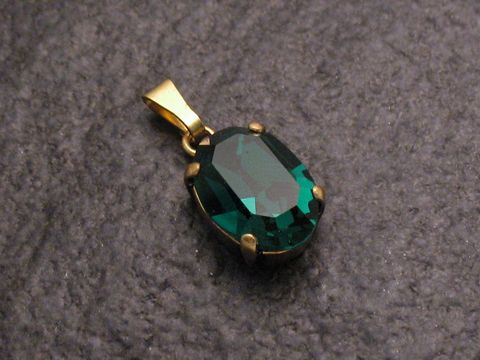 Grüner Strass Anhänger im sexy City Look in ovaler Form, gefertigt von Juwelier Harnisch, glänzender grüner Stein in goldfarbener Fassung, ideal für elegante Schmucksets.