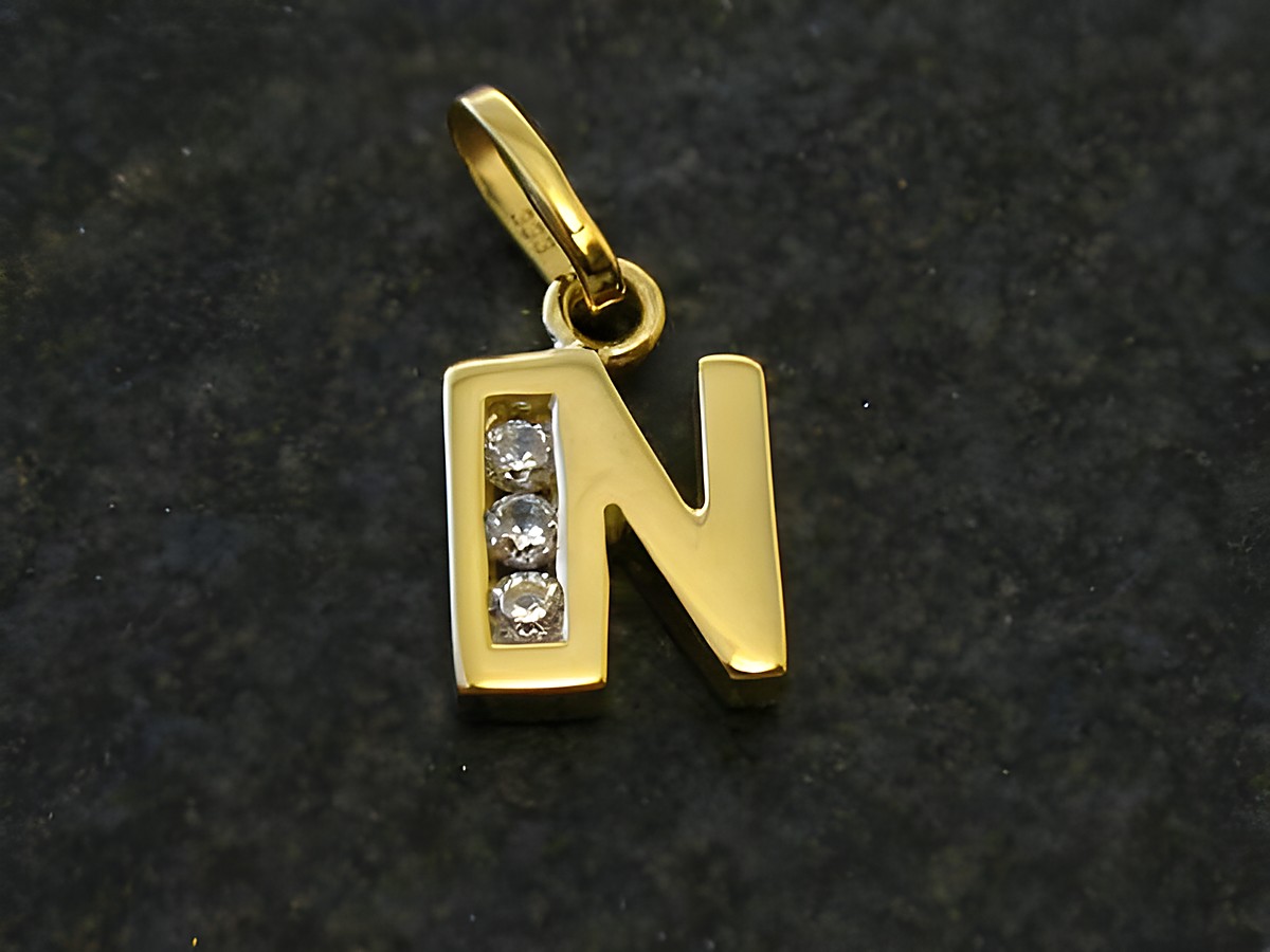 Goldener Anhänger in Form des Buchstabens N, verziert mit drei Zirkonia, Hersteller Juwelier Harnisch. Ideal als persönliches Schmuckstück oder Geschenk.