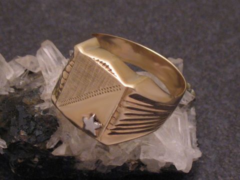Goldring mit Stern aus Gold 333 bicolor in Größe 61, hergestellt von Juwelier Harnisch, über Größe 60/19, auf einem mineralischen Untergrund.