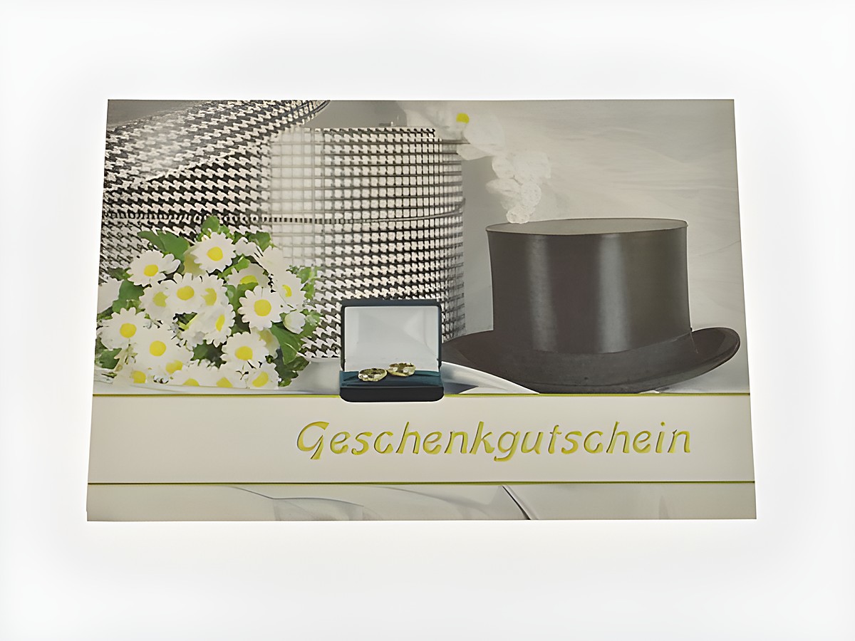 Gutscheinkarte von Juwelier Harnisch auf einer Hutschachtel mit einem Zylinder, einem kleinen Ringetui und einem Blumenstrauß. Die Karte ist elegant und einladend gestaltet.