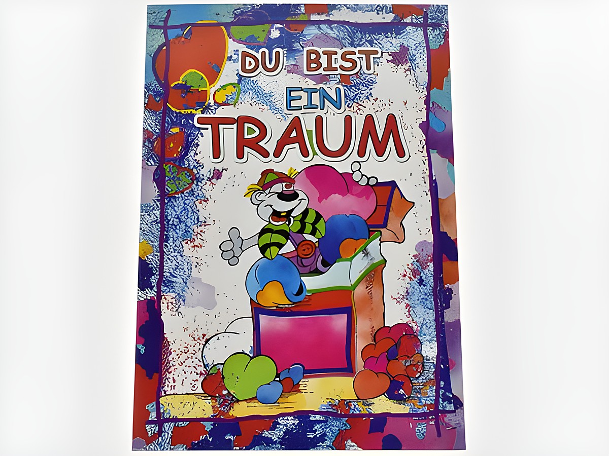 Eine bunte Grußkarte mit der Aufschrift "DU BIST EIN TRAUM". Auf der Karte sitzt eine Lümmel-Figur auf einer Geschenkbox umgeben von Herzen und bunten Formen, Hersteller: Juwelier Harnisch.