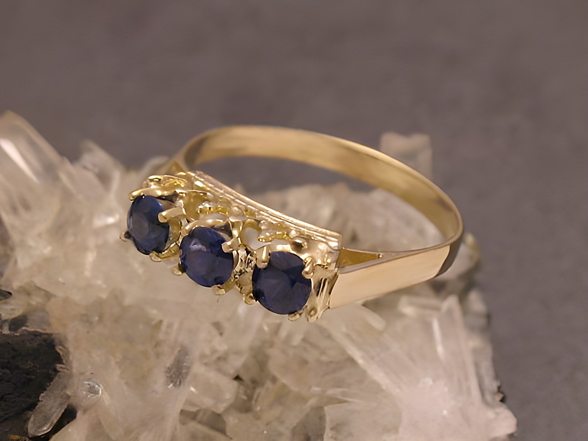 Goldring elegant Gold 333 mit drei synthetischen Saphiren, Größe 53, Hersteller Juwelier Harnisch, bis Größe 54/17,5, auf Kristallunterlage präsentiert.