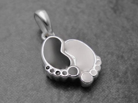 Ein niedlicher Anhänger in Form von Babyfußabdrücken aus Sterling Silber in Schwarz und Weiß, ideal als Schmuckstück für Kinder, hergestellt von Juwelier Harnisch.