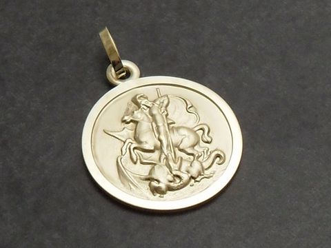 Goldanhänger mit dem Motiv des Heiligen Georg, der einen Drachen besiegt. Hersteller ist Juwelier Harnisch. Symbolisiert Schutz und Stärke als Schutzpatron.