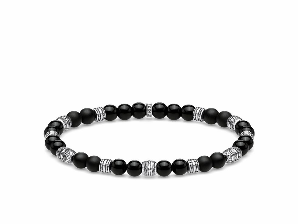 Auf dem Bild ist ein Thomas Sabo Armband aus Sterling Silber und schwarzem Obsidian zu sehen. Es hat eine Länge von 15,5 cm und besteht aus einer Kombination von matten und glänzenden schwarzen Perlen sowie silbernen Zwischenteilen.