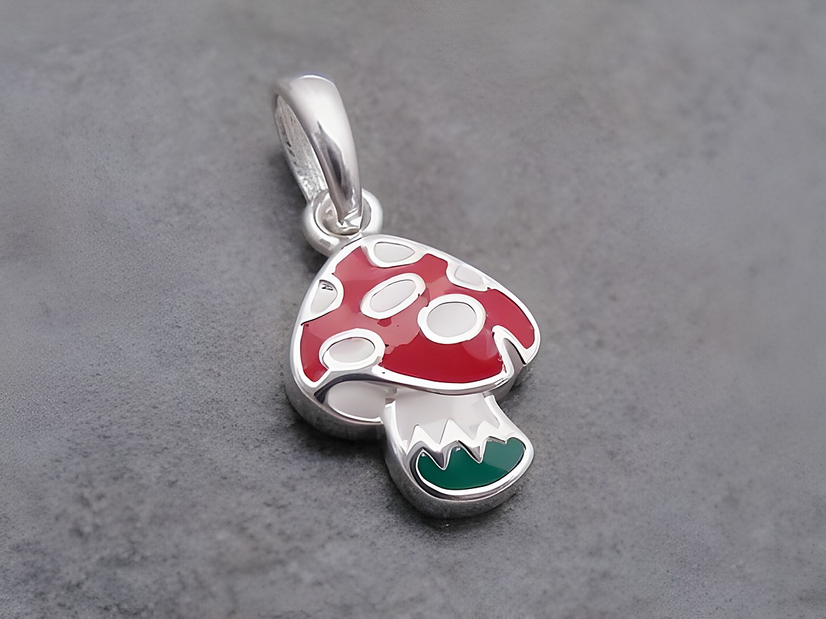 Silber Anhänger in Form eines Fliegenpilzes mit roter Kappe, weißen Punkten und einem dunkelgrünen Fuß, lackiert und von Juwelier Harnisch, goldig gestaltet.