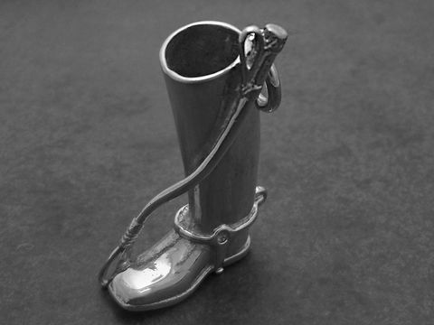 Silber Anhänger in Form eines Reitstiefels mit einer Gerte, ideal für Pferdesportliebhaber, hergestellt von Juwelier Harnisch. Schmuckdesign elegant und sportlich.