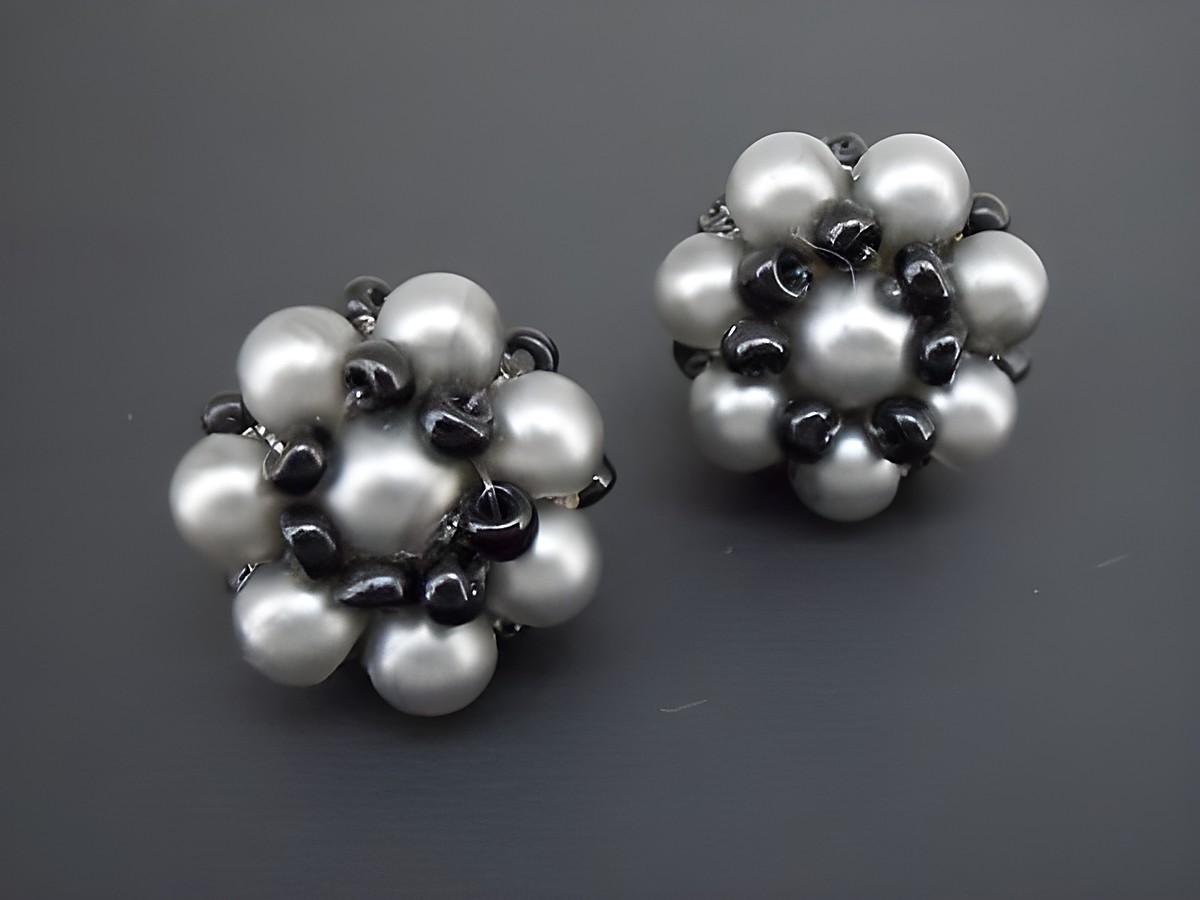 Dunkelgrau-schwarzer blumiger Ohrclip mit goldfarbenen Details und synthetischen Zuchtperlen, Hersteller Juwelier Harnisch, elegant und dekorativ.