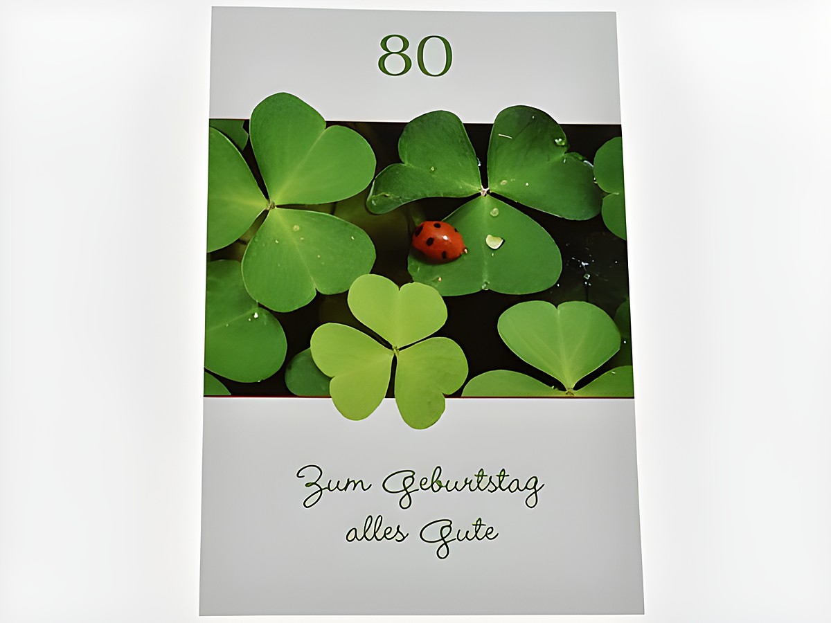 Eine Geburtstagskarte mit der Aufschrift 80, verziert mit Glücksklee und einem Marienkäfer, darunter steht Zum Geburtstag alles Gute, Hersteller Juwelier Harnisch.