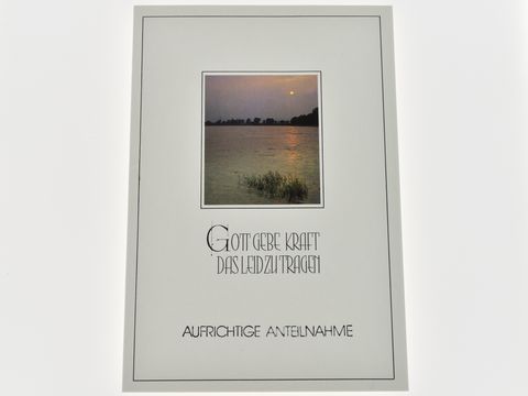 Eine Trauerkarte mit einem sanften Abendsee, der im Dämmerlicht leuchtet. Der Text "Gott gebe Kraft das Leid zu tragen" ist prominent platziert, um Trost zu spenden. Hersteller ist Juwelier Harnisch.