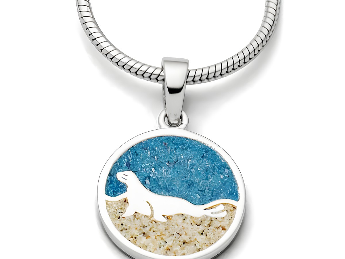 DUR Anhänger Seehund aus Sterling Silber mit einer runden Plakette, die einen stilisierten Seehund vor blauem und sandfarbenem Hintergrund zeigt.