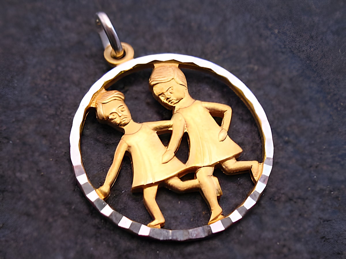 Detailreicher Anhänger aus Gold auf Silber in Form des Sternzeichens Zwillinge, gefertigt vom Juwelier Harnisch, zeigt zwei stilisierte Figuren, die tanzend dargestellt sind.
