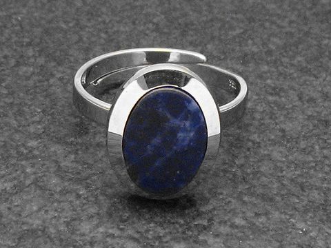 Silberring rho in ovaler Form, verstellbar, mit blauem Sodalithstein, rhodiniert, Hersteller Juwelier Harnisch auf schwarzem Untergrund.