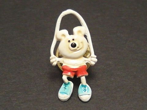 Bärchen mit Seil als Pin Anstecker von Juwelier Harnisch, der fröhliche Bär trägt rote Shorts und blaue Schuhe, ideal für eine verspielte Note auf Kleidung oder Taschen.
