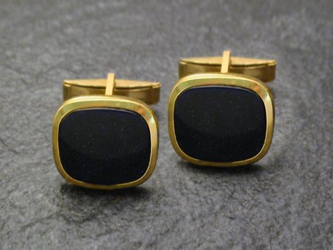 Glitzer Manschettenknöpfe in goldfarbenem Glitzer-Look von Juwelier Harnisch, mit quadratischem Design und dunkler Oberfläche, ideal für elegante Anlässe.