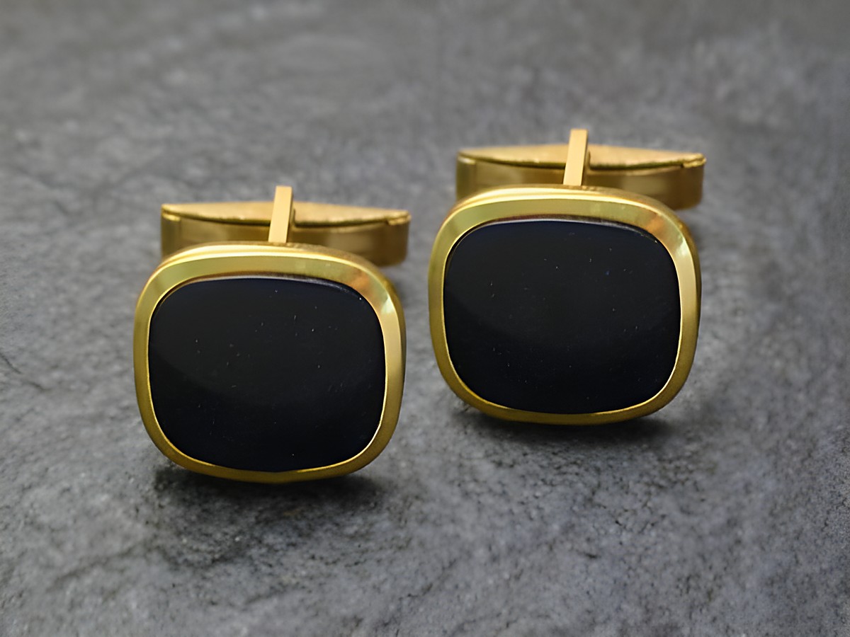 Glitzer Manschettenknöpfe in goldfarbenem Glitzer-Look von Juwelier Harnisch, mit quadratischem Design und dunkler Oberfläche, ideal für elegante Anlässe.
