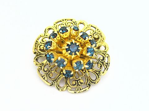 Damen Brosche im Sexy City Look in Blau, rund, hergestellt von Juwelier Harnisch, mit funkelnden Strasssteinen in blauer Farbe und filigranem goldfarbenem Design.